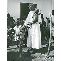 Vintage photo of Missionary priest, Pere James looking after the malnourished children greatly affected by war in Biafra.