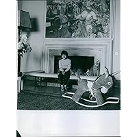 Vintage photo of Princess Yasmin Aga Khan smiling and sitting by the fireplace.