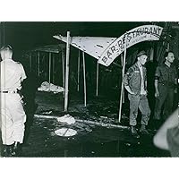 Vintage photo of Soldiers standing in front of a ruined Bar Restaurant at night in Saigon during the war in Vietnam, 1965.