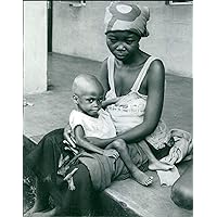 Vintage photo of A famished looking woman holding her young malnourished child. Biafra.
