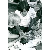Vintage photo of Woman giving treatment to a child suffering from malnutrition during the war, Vietnam, 1979.