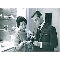 Vintage photo of Man holding a flower in his hands, woman standing beside, talking to him and smiling.1961royalty laos