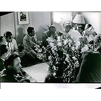 Vintage photo of Men in a room with flowers having a conversation in Laos. June 19, 1961.