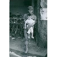Vintage photo of A Vietnamese soldier in Saigon cuddling a child.