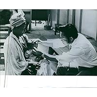 Vintage photo of A leprosy doctor checking up the eyes of a child.